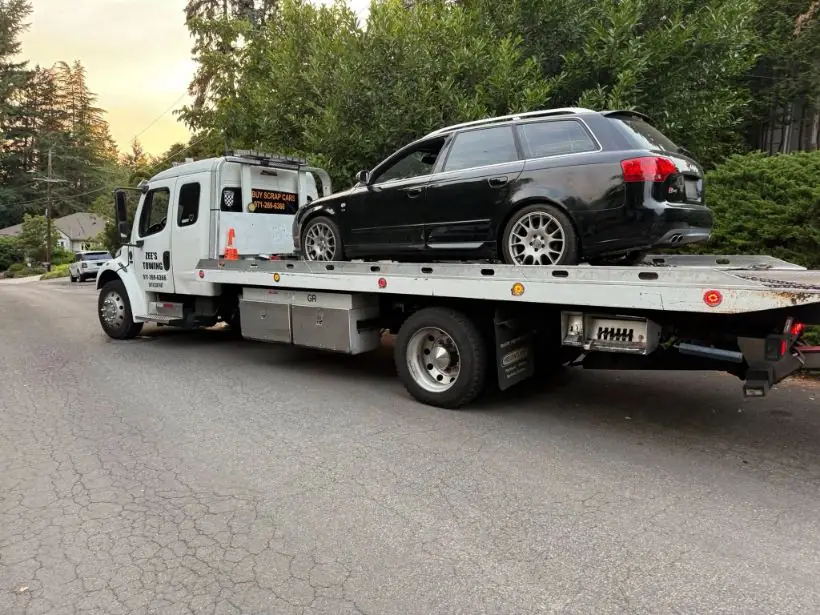 Flatbed towing an Audi wagon at dusk near Clackamas, Oregon