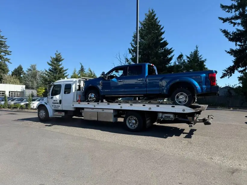Heavy-duty flatbed towing a Ford dually truck in Clackamas